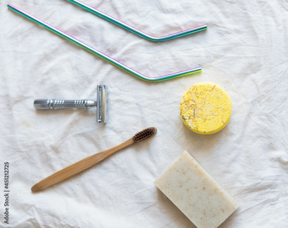Zero waste product, close up caption. Bamboo toothbrush, solid shampoo, metal razor, metal straws and solid hand soap. Sustainable bathroom products on a white background.