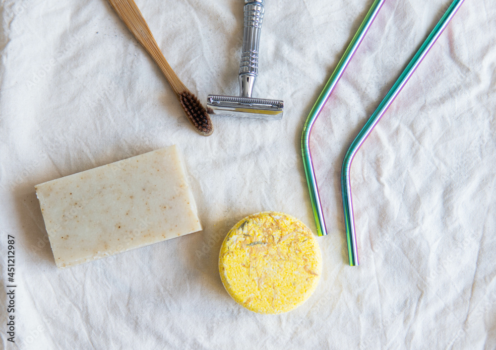 Zero waste product, close up caption. Bamboo toothbrush, solid shampoo, metal razor, metal straws and solid hand soap. Sustainable bathroom products on a white background.