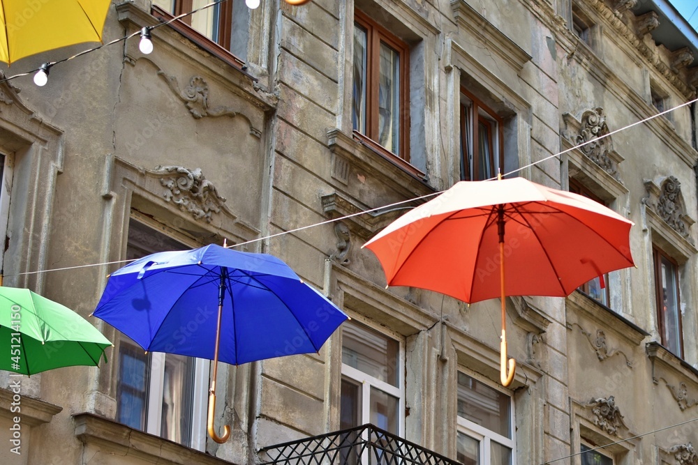 multi colored umbrellas hang on background of the old town house
