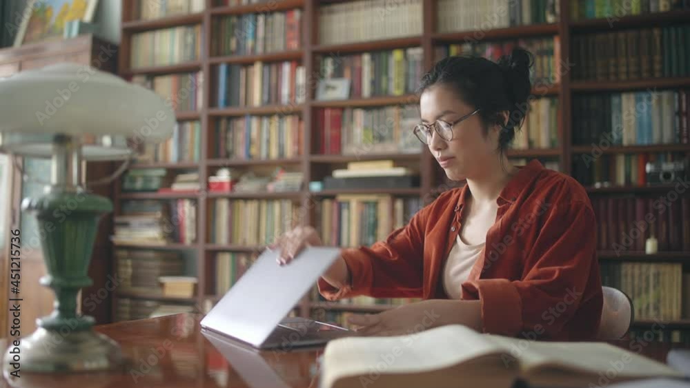 Young woman asian student coming into library with laptop to study or work Young woman asian student coming into library with laptop to study or work
