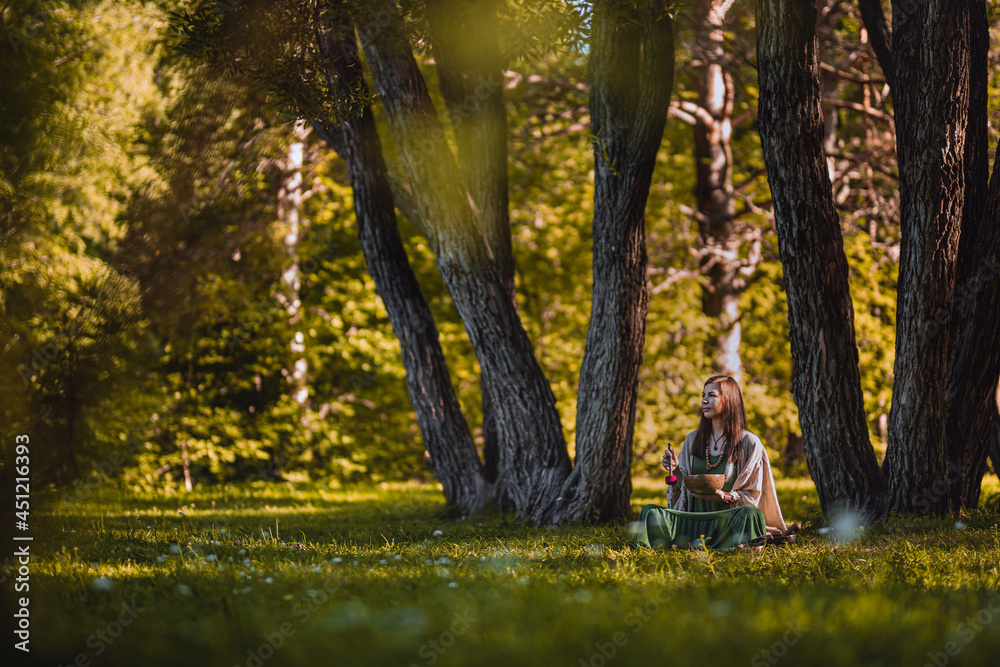yogi woman sitting in the forest and playing music bowls yogi woman sitting in the forest and playing music bowls