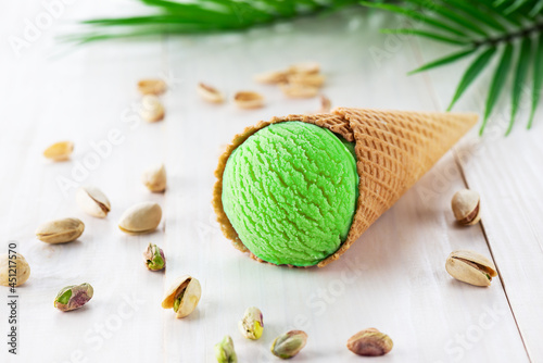 Pistachio ice cream with a branch of a palm tree on a wooden table.