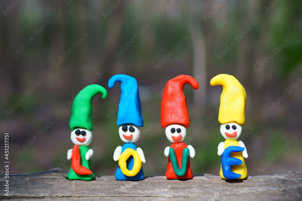 Naklejka premium Figures of colorful dwarfs on a colored background. They hold letters in their hands. The inscription is love.
