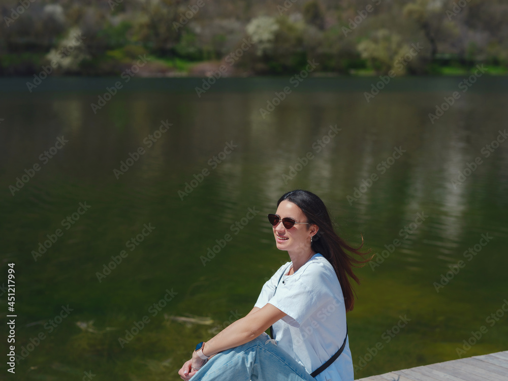Young woman enjoying beauty of nature mountain lake. Adventure travel in Europe. Lady on wooden bridge on background with forest. Young woman enjoying beauty of nature mountain lake. Adventure travel in Europe. Lady on wooden bridge on background with forest.