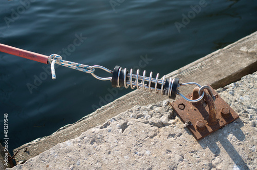 Parking the yacht to pier with mooring spring on rusty metal ring