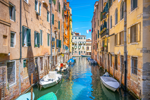 Lovely Venetian nook on sunny summer day. Narrow water canal with boats and residential houses along. Venice, Italy © pyty