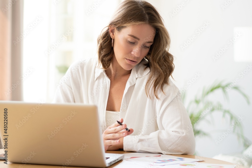 Beautiful young woman working from home on laptop.