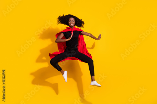 Full body photo of happy nice dark skin woman jump up wear cape super hero isolated on yellow color background