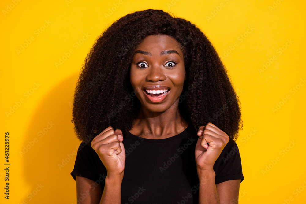 Photo of funny young lady hands fists wear black t-shirt isolated on vivid yellow color background Photo of funny young lady hands fists wear black t-shirt isolated on vivid yellow color background