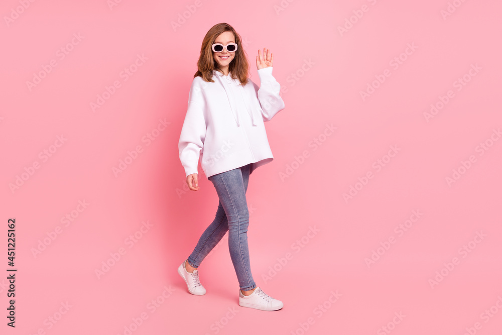 Full length body size view of pretty cheerful girl walking waving hi hello isolated over pink pastel color background Full length body size view of pretty cheerful girl walking waving hi hello isolated over pink pastel color background