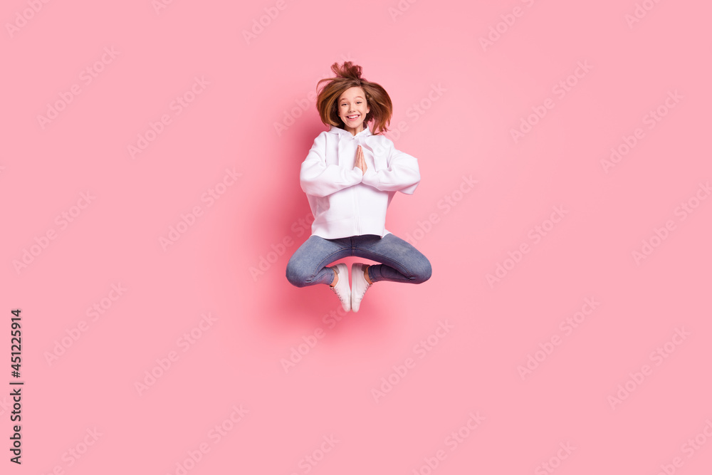 Full length body size girl jumping high practising yoga in white hoodie isolated pastel pink color background