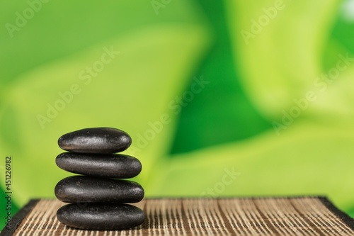 Canvas Print Balancing Pebbles black stones on green background