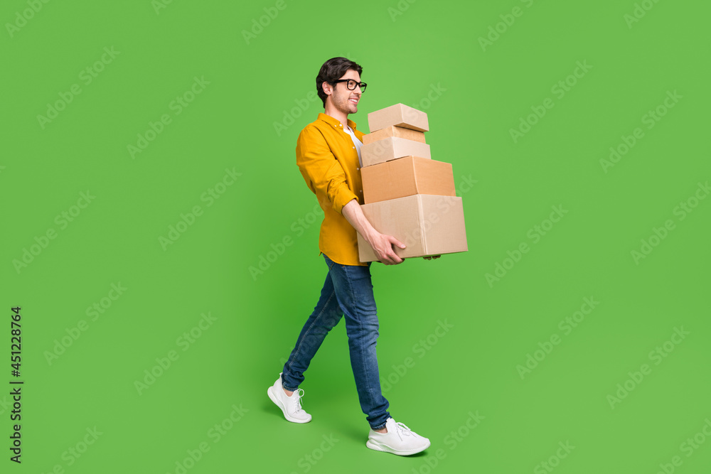 Full size profile side photo of young handsome positive man go walk moving new home isolated on green color background Full size profile side photo of young handsome positive man go walk moving new home isolated on green color background