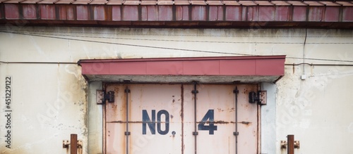 Old factory warehouse with red discolored roof and black no.4 on rusty door banner