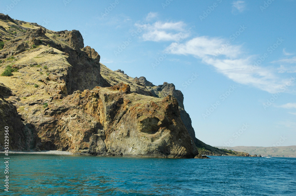 Coastal cliffs, view from the sea. Rocks in the form of animals hang over the sea. Rocky coast. Crimea.