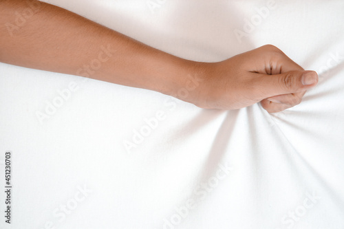 Young woman in bed clutching tightly her hand Bed pulling and grab white bed sheet.