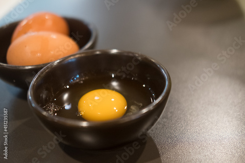 Foto Fresh raw egg yolk for eating with shabu and sukiyaki in a black bowl