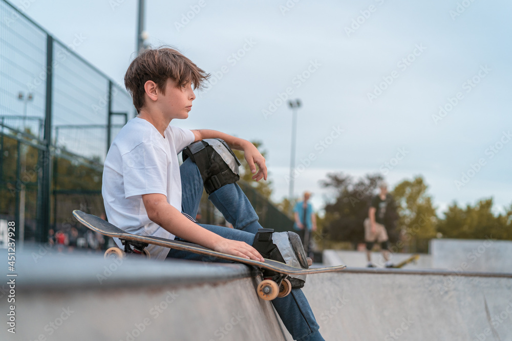 Skateboarder sitting on ramp in skate park Skateboarder sitting on ramp in skate park