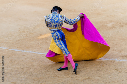 Unrecognizable bullfighter with cape on sandy arena