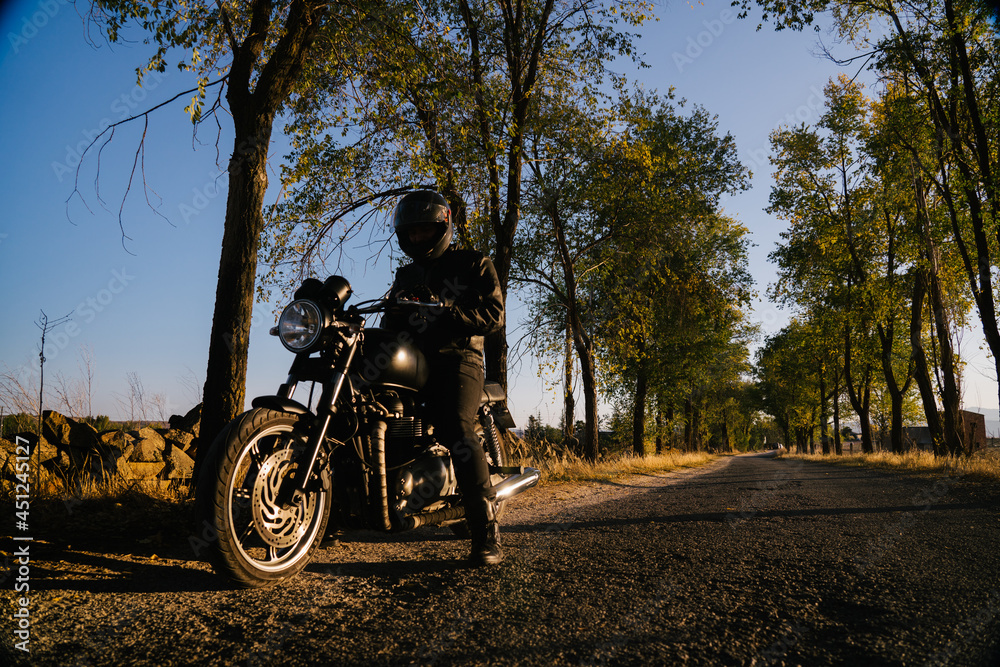 Focused Mature Male Biker Preparing For Riding In Sunny Day Focused Mature Male Biker Preparing For Riding In Sunny Day