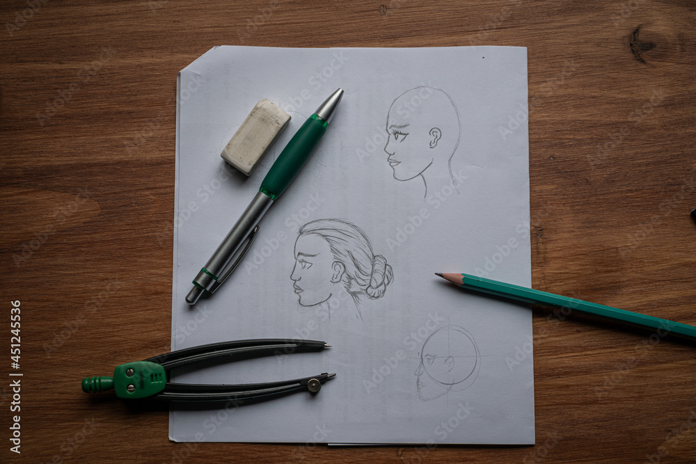 A beginner's drawing of a woman's face. On a wooden table. A beginner's drawing of a woman's face. On a wooden table.