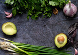 An overhead view of a delicious assortment of farmhouse fresh herbs made from onions and avocados, against a dark background. A summary space for your product or label.