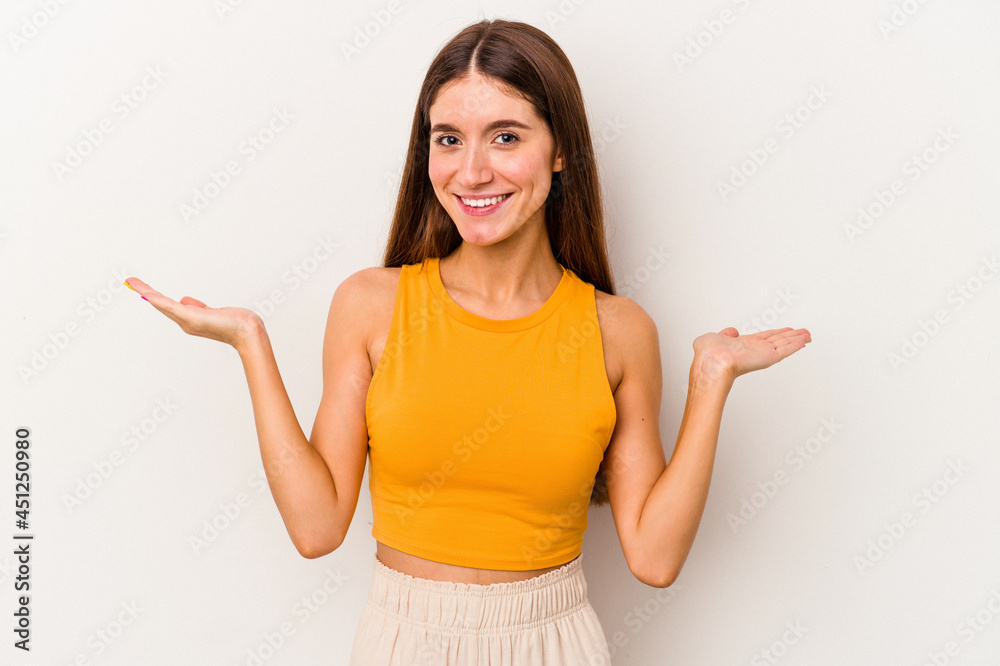 Young caucasian woman isolated on white background makes scale with arms, feels happy and confident. Young caucasian woman isolated on white background makes scale with arms, feels happy and confident.