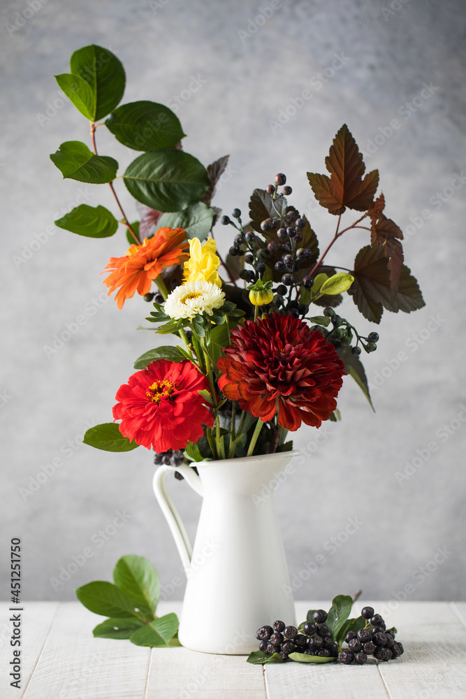 Bouquet of fresh flowers branches and black berries on table. Autumn holiday concept.