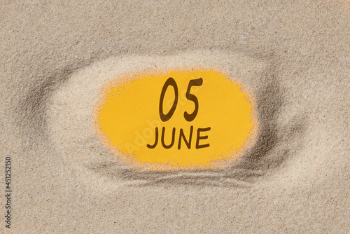 June 5. 5th day of the month, calendar date. Hole in sand. Yellow background is visible through hole. Summer month, day of the year concept photo
