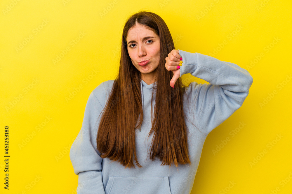 Young caucasian woman isolated on yellow background showing a dislike gesture, thumbs down. Disagreement concept. Young caucasian woman isolated on yellow background showing a dislike gesture, thumbs down. Disagreement concept.