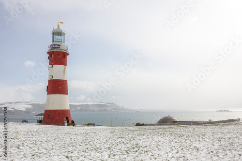 Plymouth Hoe lighthouse on the coast, in the snow