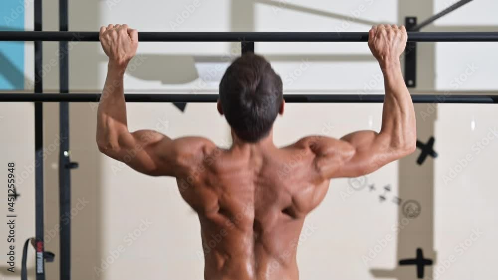 Crossfit athlete doing pull-ups at the gym. Handsome man doing functional training. High quality 4k footage