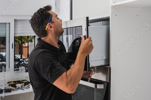 Man placing a microwave inside the hole of a new kitchen cabinet