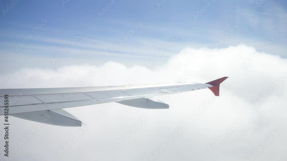 Flying on a turbo jet plane in the clouds. Through the window you can see white clouds and the wing of the plane. High altitude. Flying on a turbo jet plane in the clouds. Through the window you can see white clouds and the wing of the plane. High altitude.