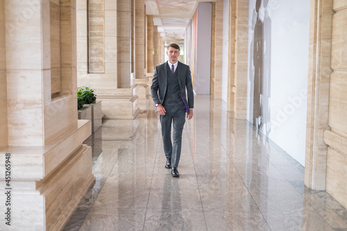 Businessman wearing grey suit and walking near office buiding. High quality photo © Aleksandr