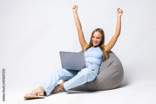 Portrait of cheerful woman with laptop sitting in beanbag on white background © F8  \ Suport Ukraine
