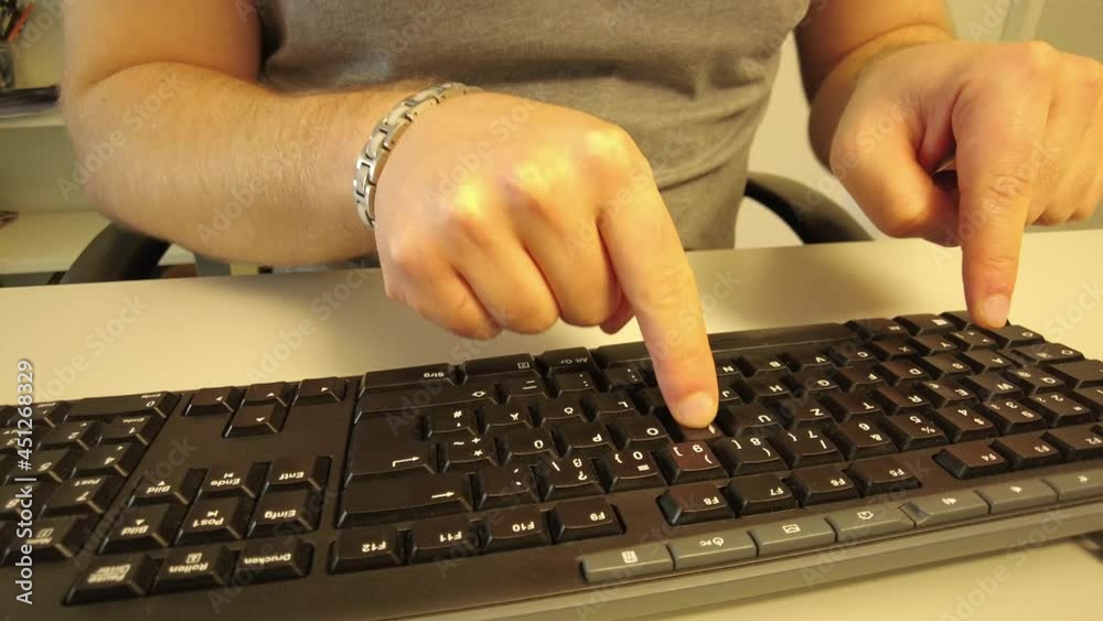 A man Typing slowly with 2 fingers on a keyboard
