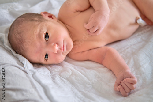 A newborn baby in a diaper is lying naked on the bed. Child boy in a cocoon on a cot.