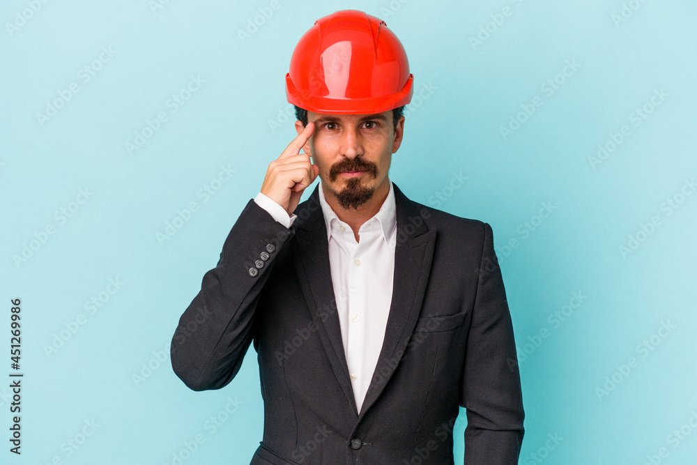 Young architect caucasian man isolated on blue background pointing temple with finger, thinking, focused on a task. Young architect caucasian man isolated on blue background pointing temple with finger, thinking, focused on a task.