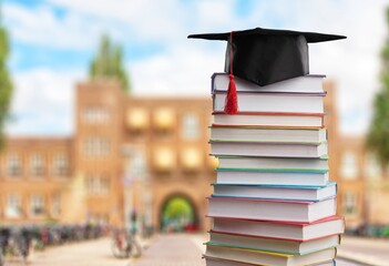 Pile school books with classic black graduation hat