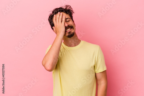 Young caucasian man isolated on pink background laughing happy, carefree, natural emotion. © Asier