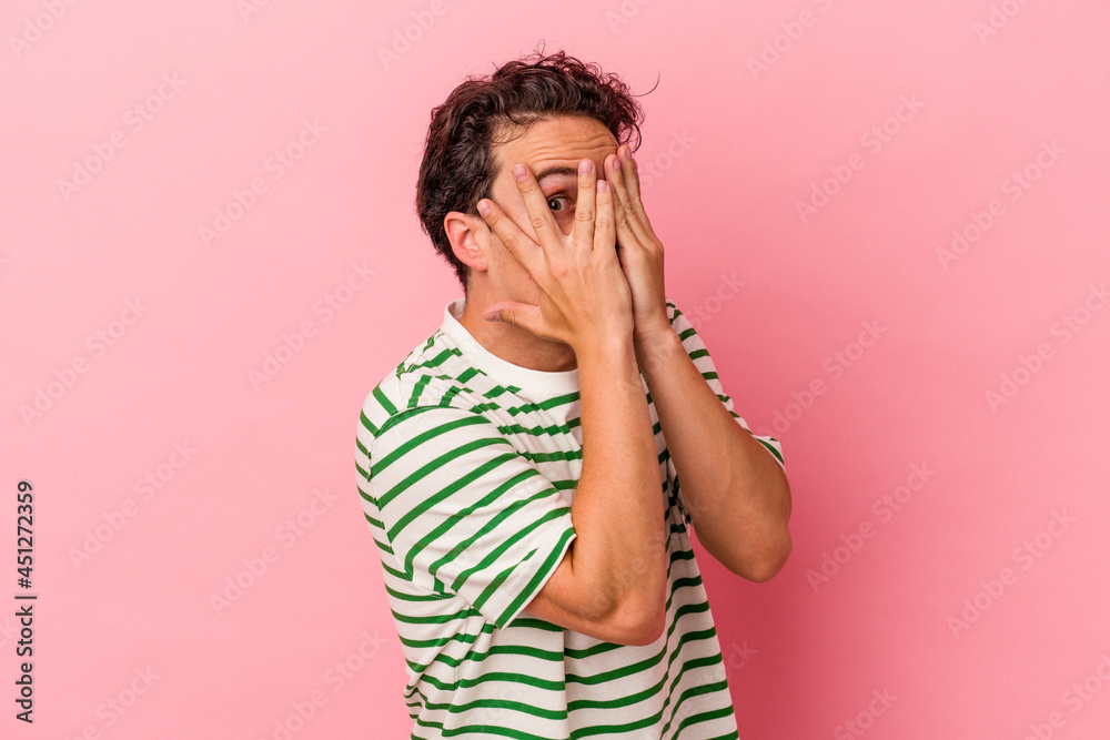 Young caucasian man isolated on pink background blink through fingers frightened and nervous. Young caucasian man isolated on pink background blink through fingers frightened and nervous.