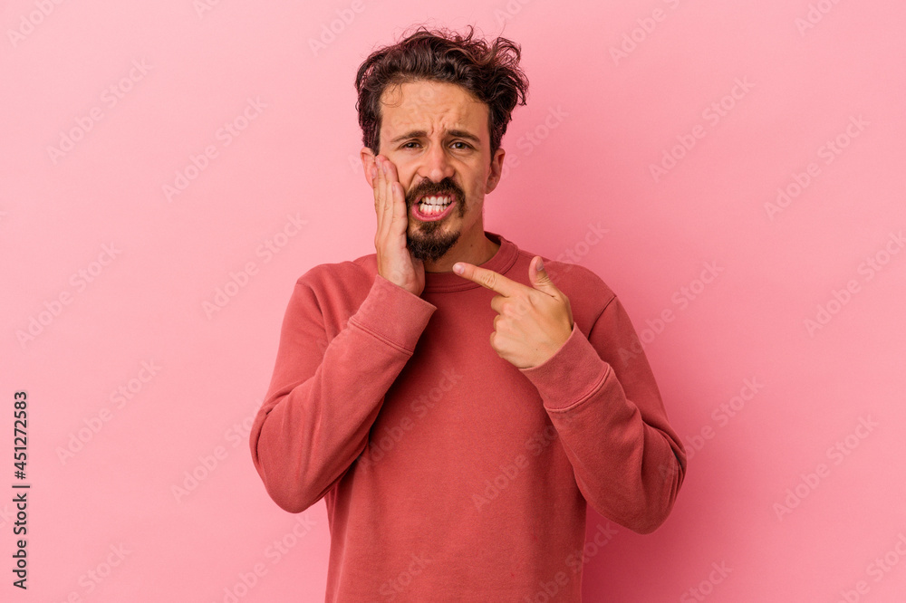 Young caucasian man isolated on pink background having a strong teeth pain, molar ache.