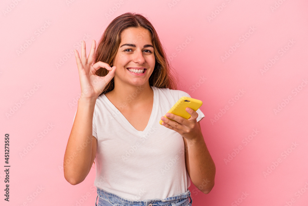 Young caucasian woman using mobile phone isolated on pink background cheerful and confident showing ok gesture. Young caucasian woman using mobile phone isolated on pink background cheerful and confident showing ok gesture.