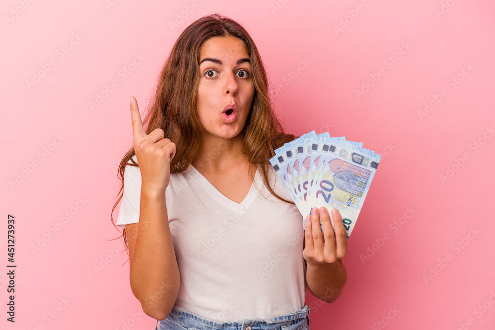 © Asier - Young caucasian woman holding bills isolated on pink background  having some great idea, concept of creativity.