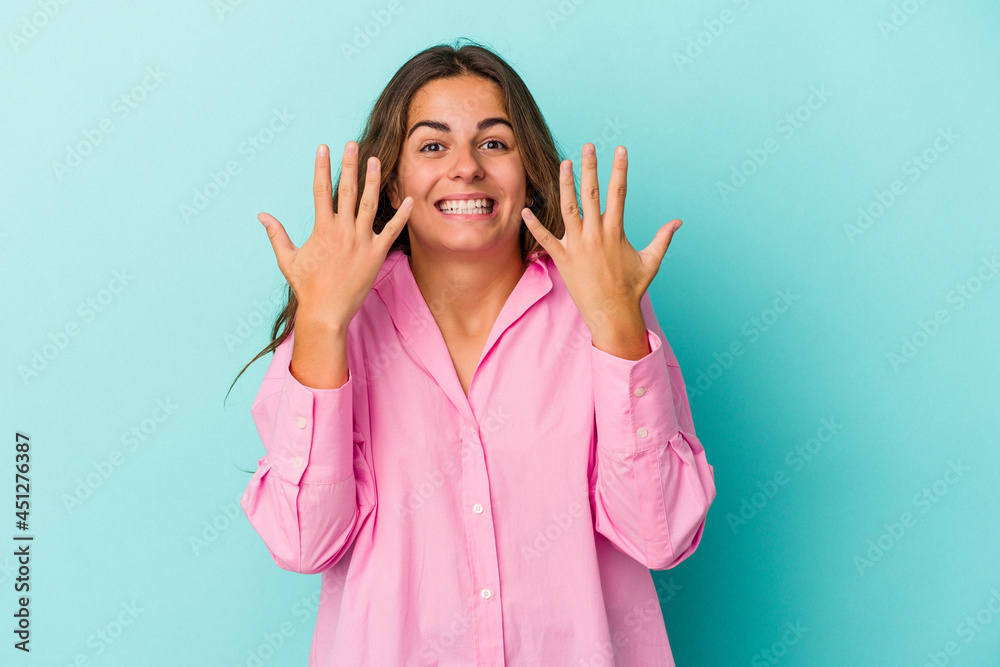 Fototapeta premium Young caucasian woman isolated on blue background showing number ten with hands.