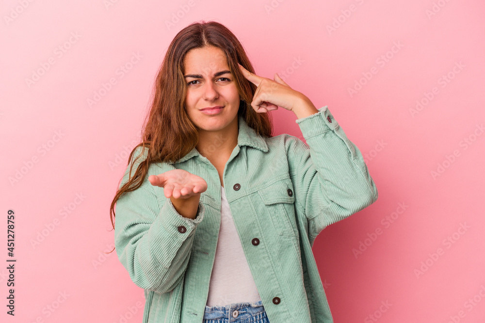 Young caucasian woman isolated on pink background  holding and showing a product on hand.