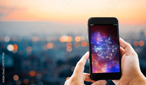 Astrological zodiac horoscope Mobile application concept.Man hands holding mobile phone on blurred city as background