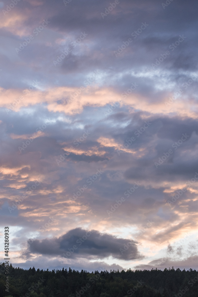 Wolken Über Nadelwald am Abend mit Abendrot und blauem Himmel