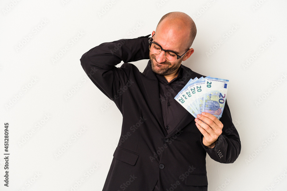 Young business bald man holding bills isolated on white background touching back of head, thinking and making a choice. Young business bald man holding bills isolated on white background touching back of head, thinking and making a choice.